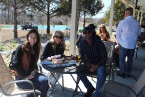 People smiling with flights of wine sitting on the patio