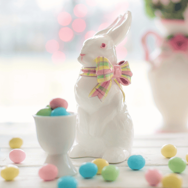Porcelain Easter bunny with pink, green and yellow bow and pink, green, yellow, and blue tiny easter eggs surrounding it and in a tiny cup